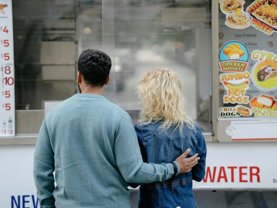 Couple reviewing food menu prices at a walk-up counter representing transparent pricing