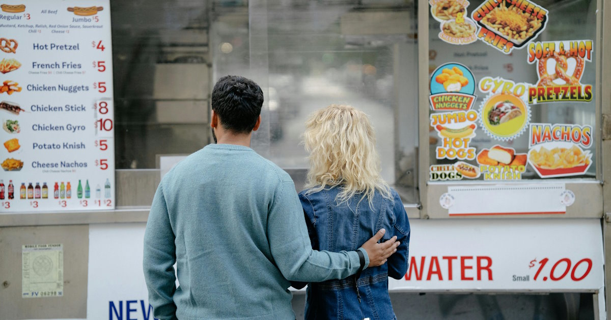 Couple reviewing food menu prices at a walk-up counter representing transparent pricing